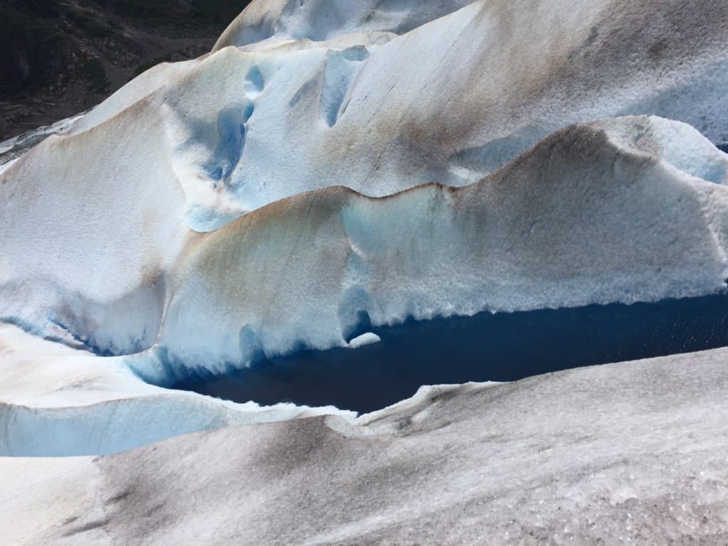 Top of a crevasse with blue water on a glacier
