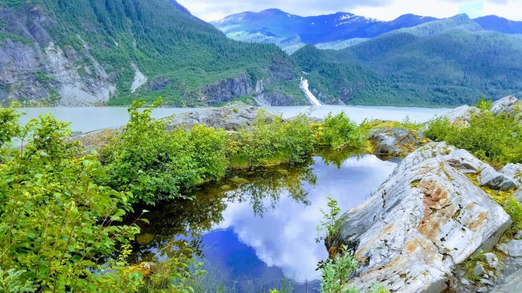 Ocean with mountains in the background and a waterfall flowing into the ocean