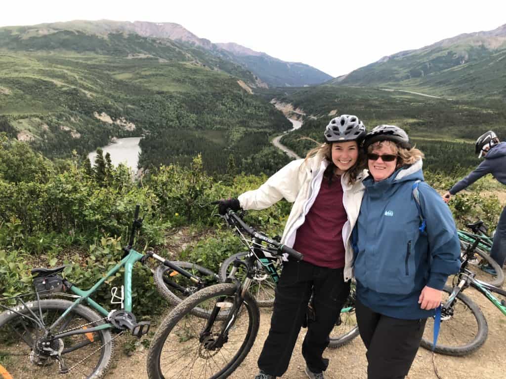 2 female friends with bicycles on top of a mountain