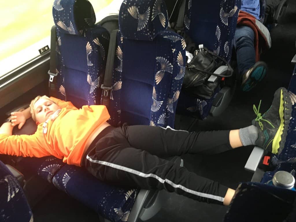 Small boy laying across two seats on a bus