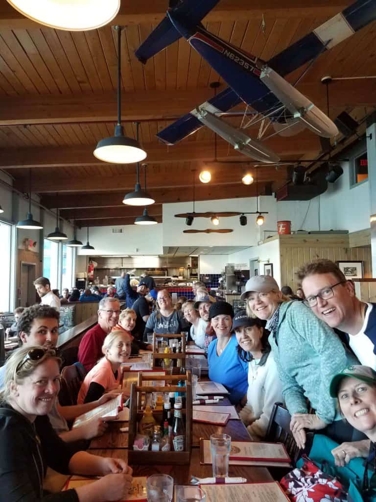 a group of 19 sitting at a table inside a restaurant