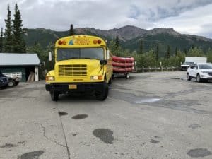 Yellow school bus carying a trailer of rafts