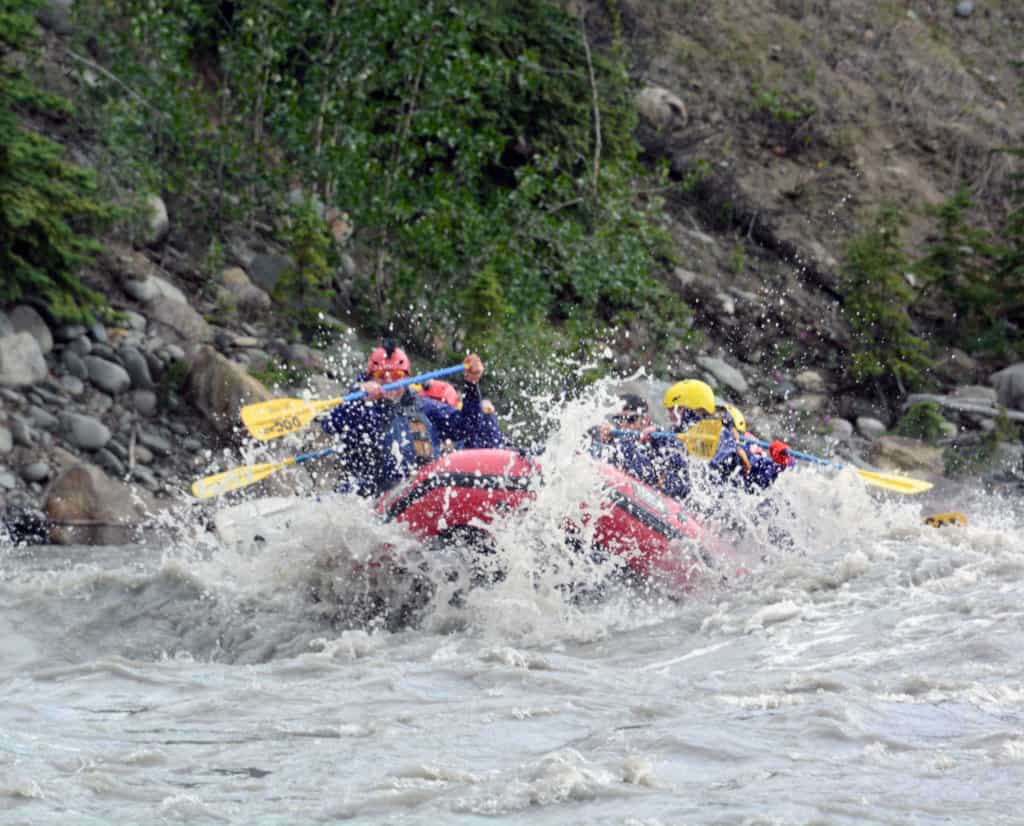 A raft in whitewater rapids with people in the raft