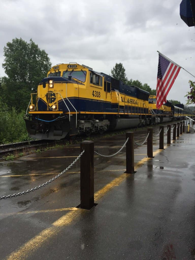 Blue and yellow train arriving into station with American flag