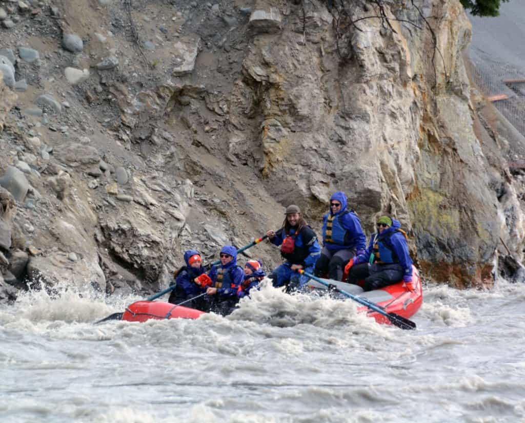 A raft in whitewater rapids with people in the raft