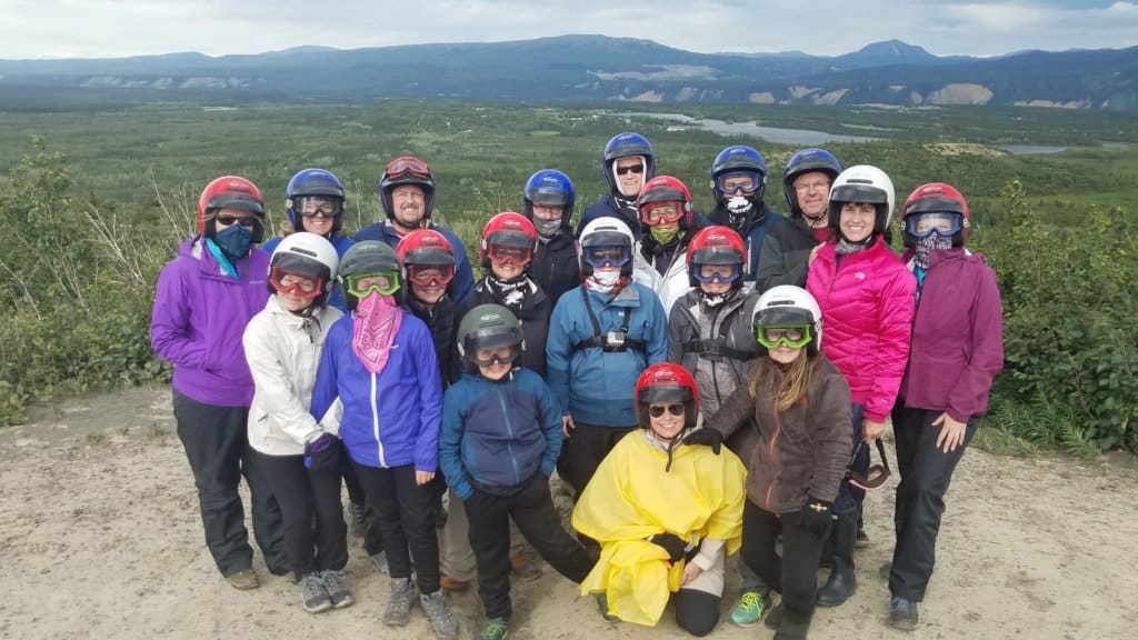 A group of friends wearing helmets with mountains in the background