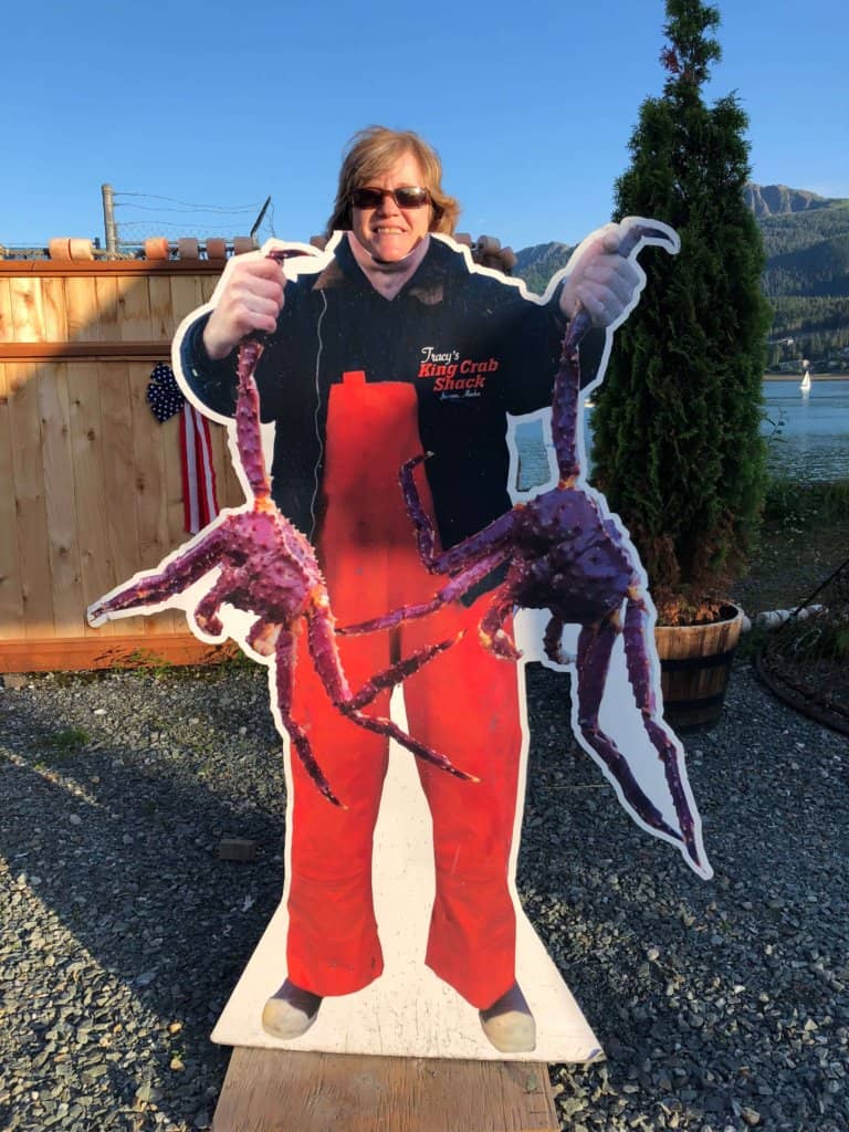 a female standing behind a cut out of someone holding king crabs