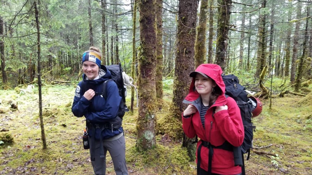 2 females wearing rain jackets and a backpack