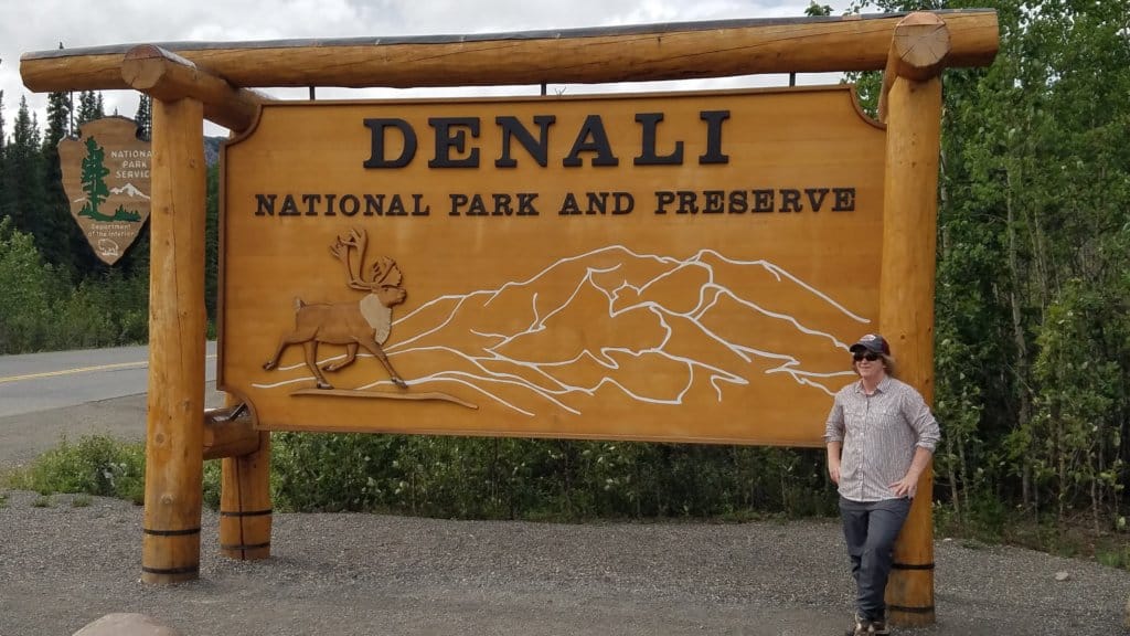 Female standing in front of a sign reading Denali National Park