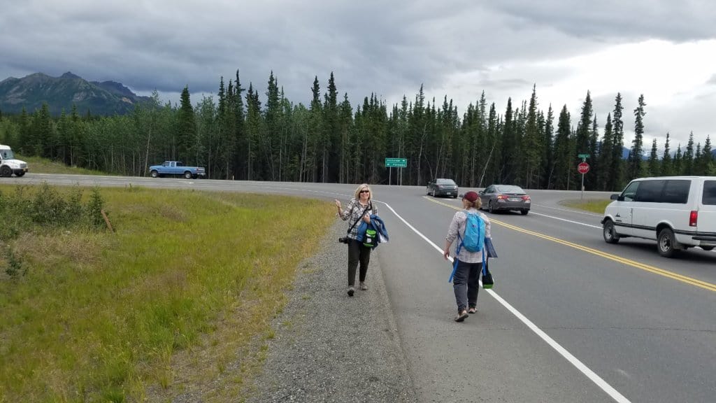 2 females standing side of road hitchhiking