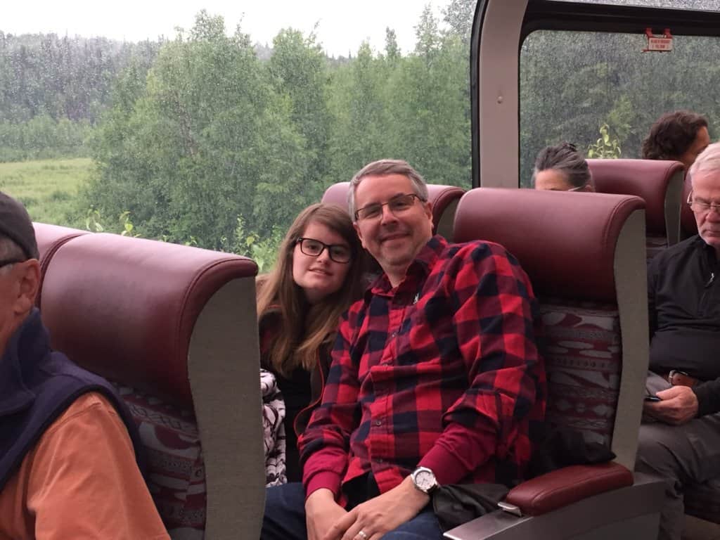 A father and daughter riding on a train