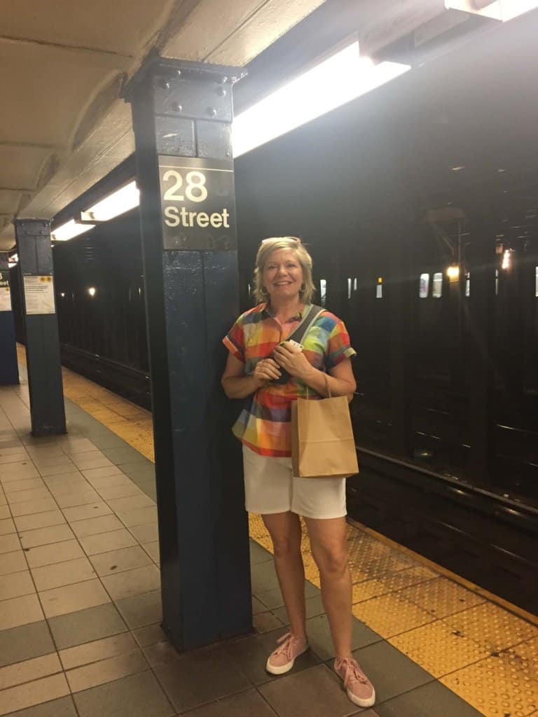 Female waiting on a subway train at 28th Street wearing white shorts and colorful top