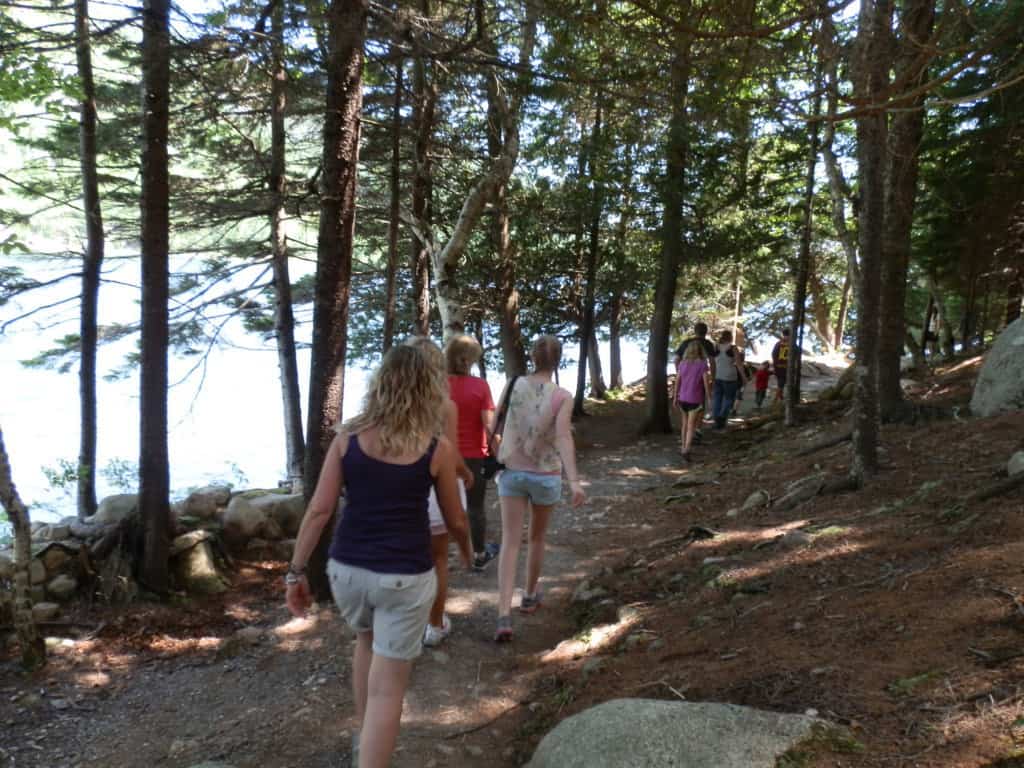 a group of people wlking along a path close to a body of water