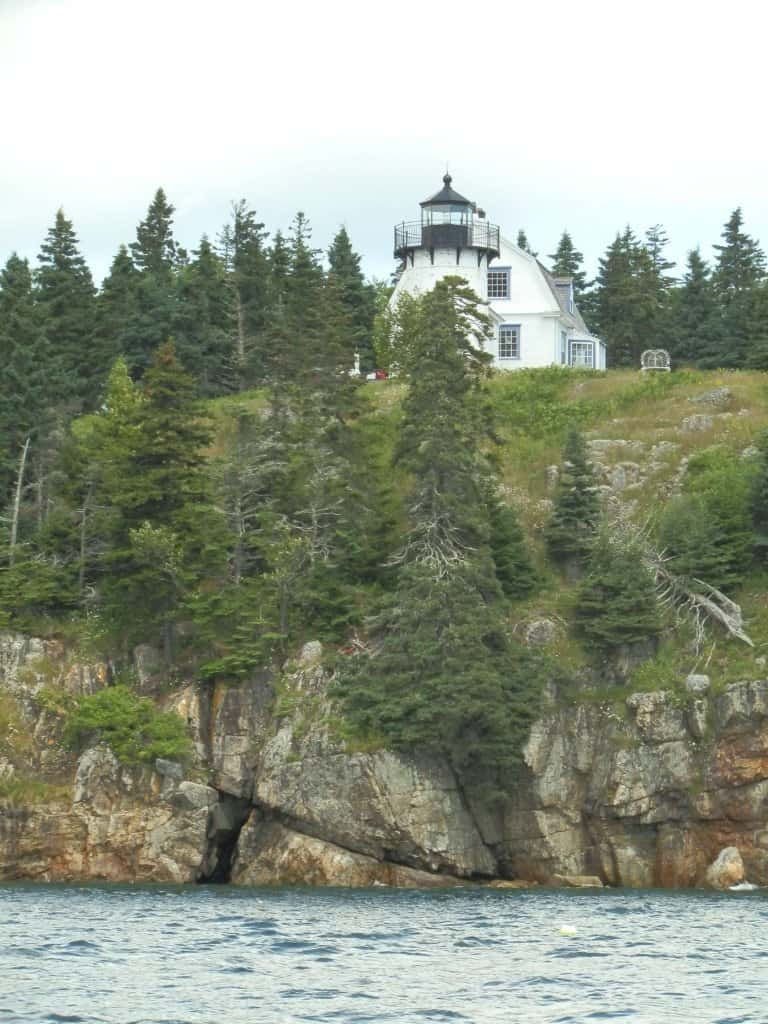 a big white lighthouse on a hill along the coast