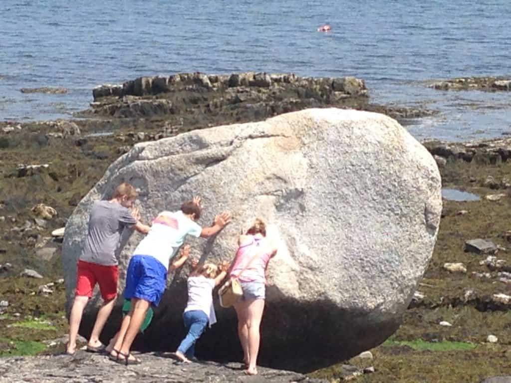 4 kids pretending to push a giant rock
