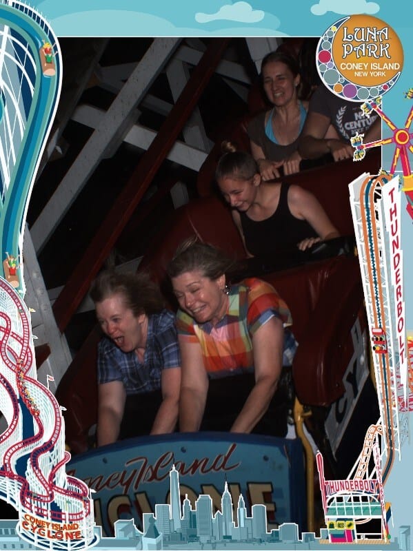 2 females smiling on the front car of a roller coaster