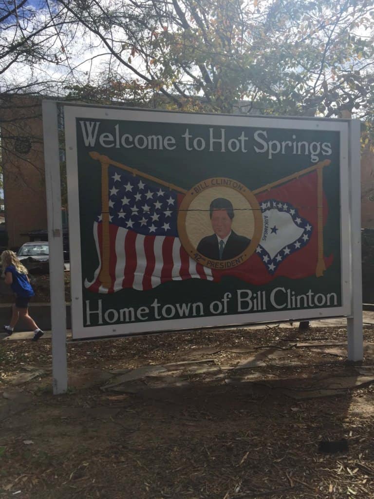 Outside sign reading Welcome to Hot Springs, Hometown of Bill Clinton with his picture in the center