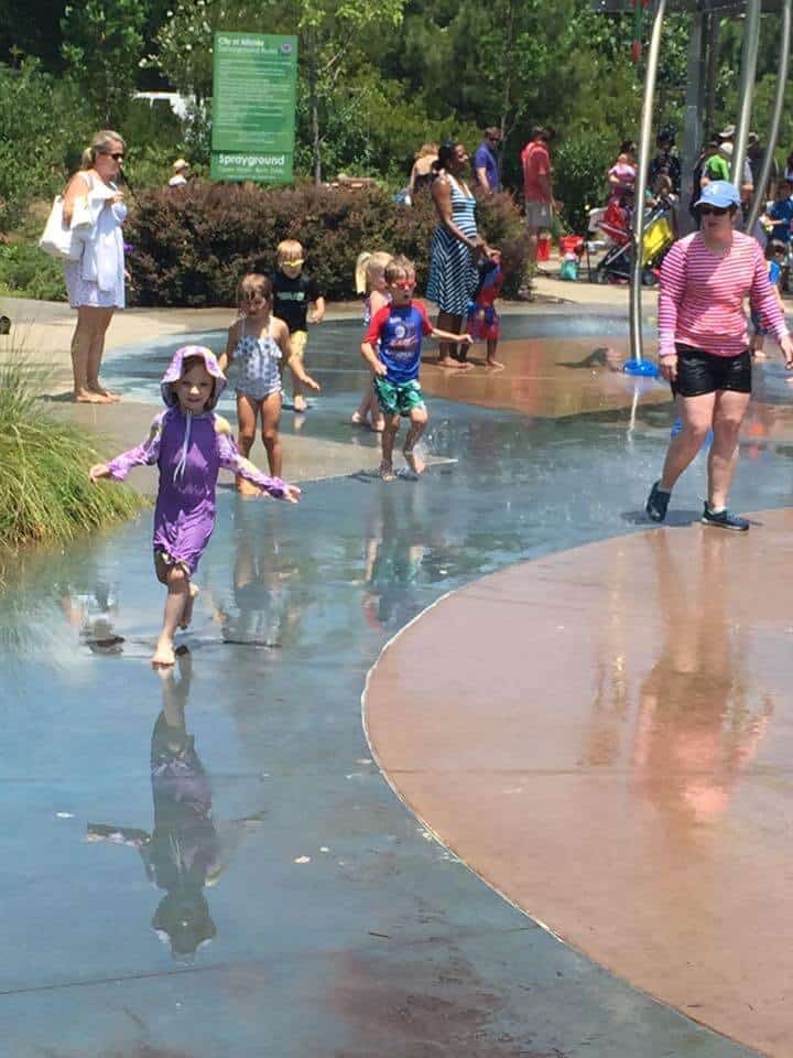 a small girl running in spraying water at a park