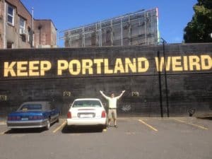 man in front of sign reading Keep Portland Weird