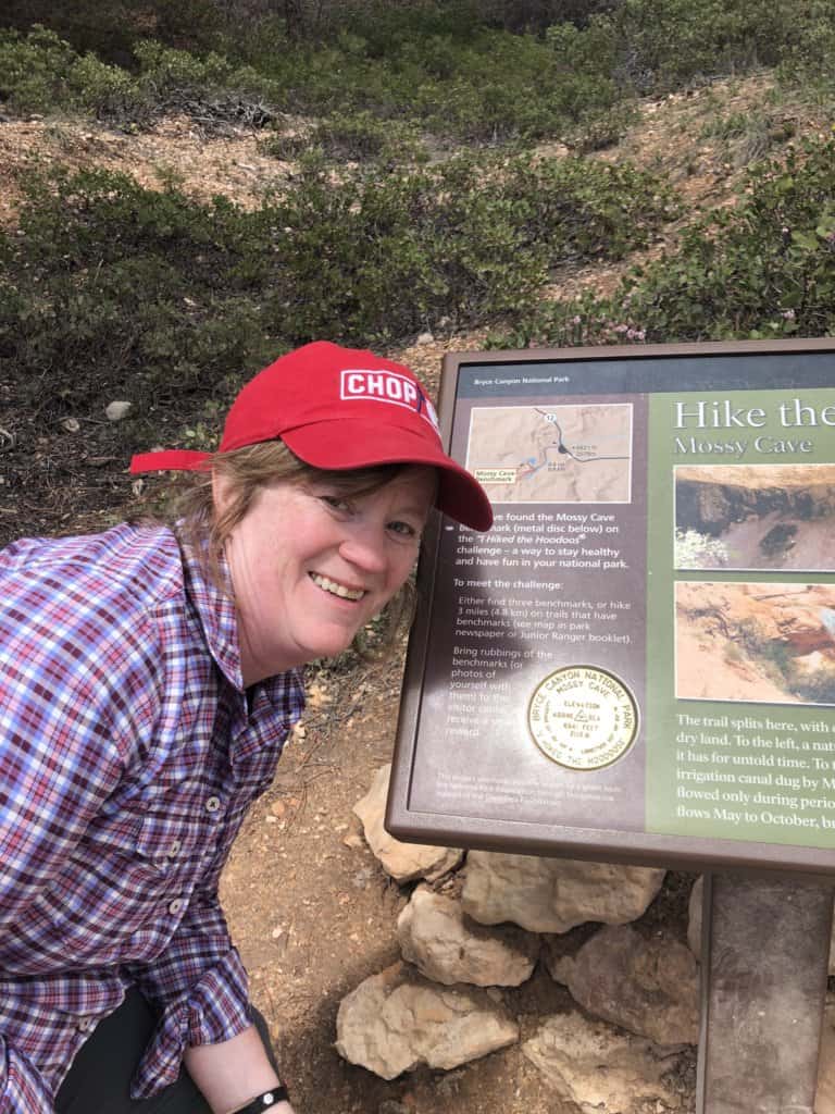 female in front of a sign reading Hike the Hoodoos