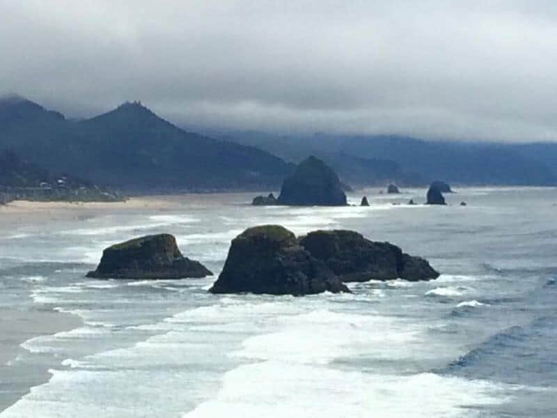 ocean with mountains in the background and rocks in the middle of the ocean