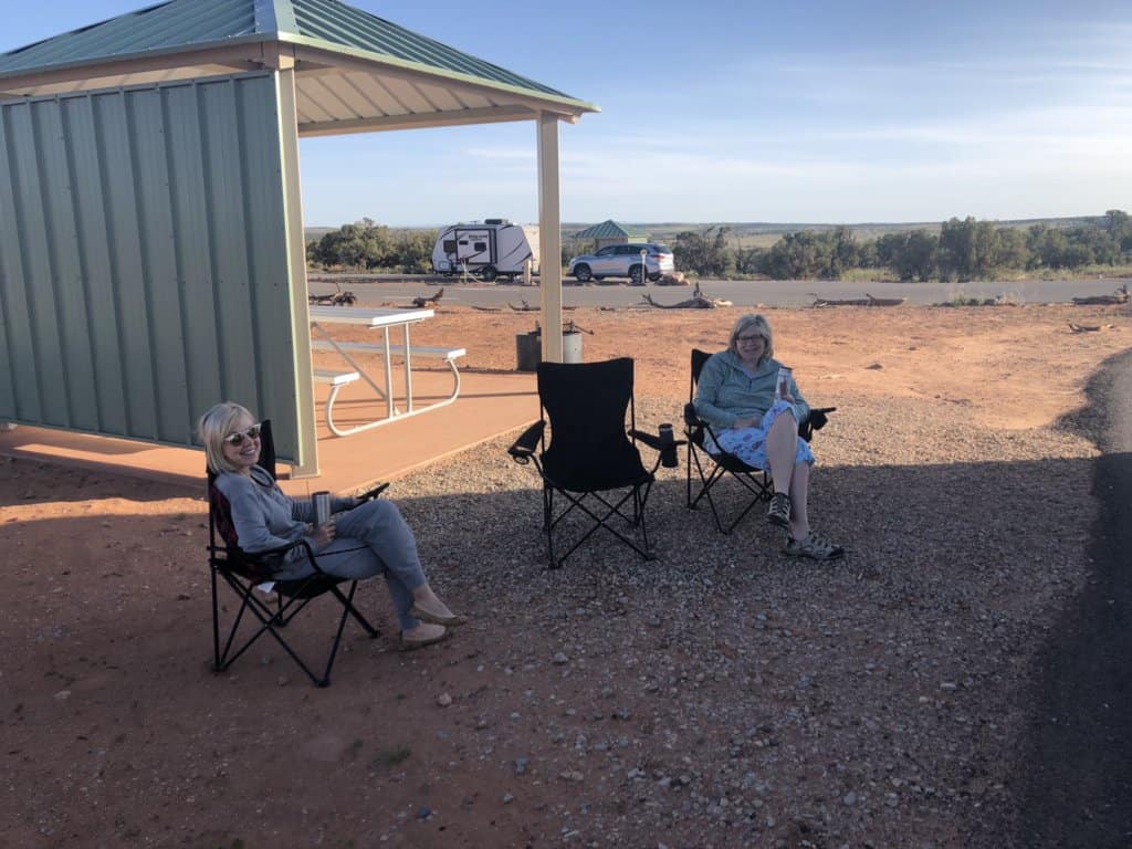2 females sitting in camping chairs at a campsite