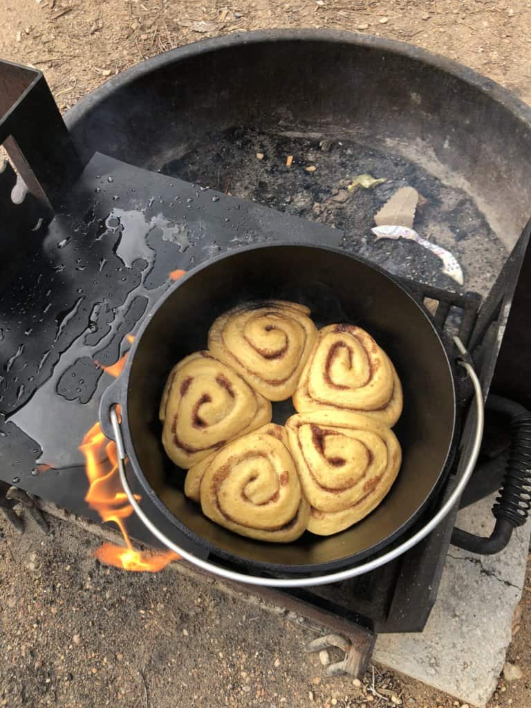 cinnamon rolls in a pot over a campfire