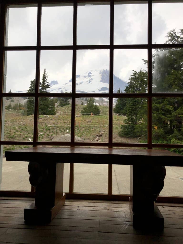 bench in front of window with snow capped mountain outside window